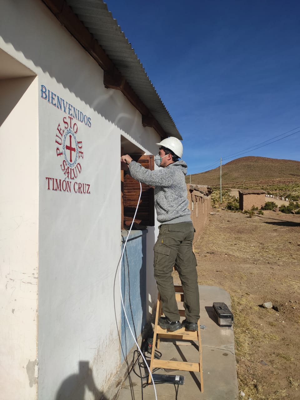 Un técnico instala una antena de internet en el Centro de Salud de Timón Cruz, en Jujuy con los cerros a lo lejos.
