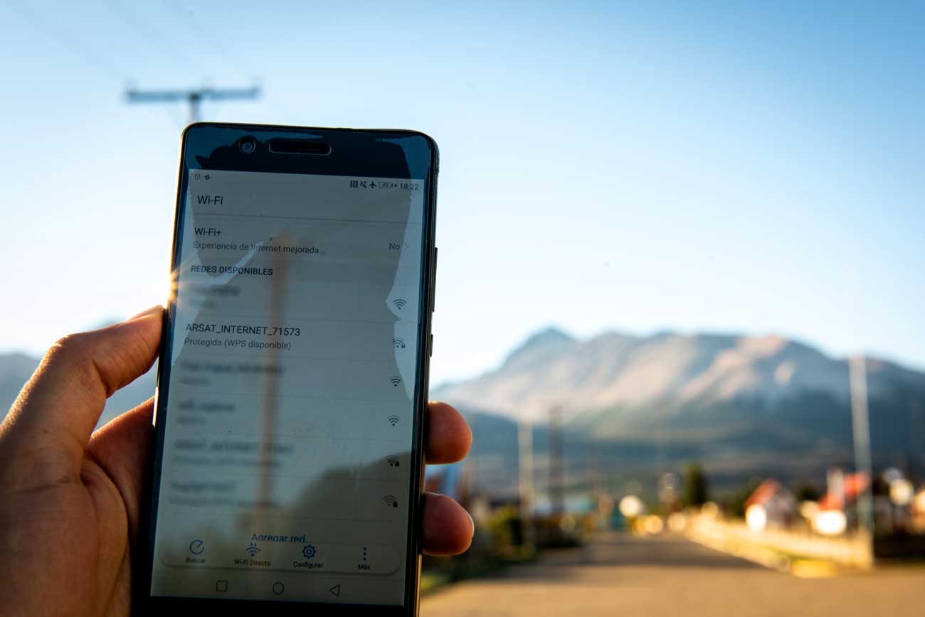 Una mano sostiene un teléfono celular que muestra la red wifi pública de Arsat en un pueblo cordillerano de la Patagonia.