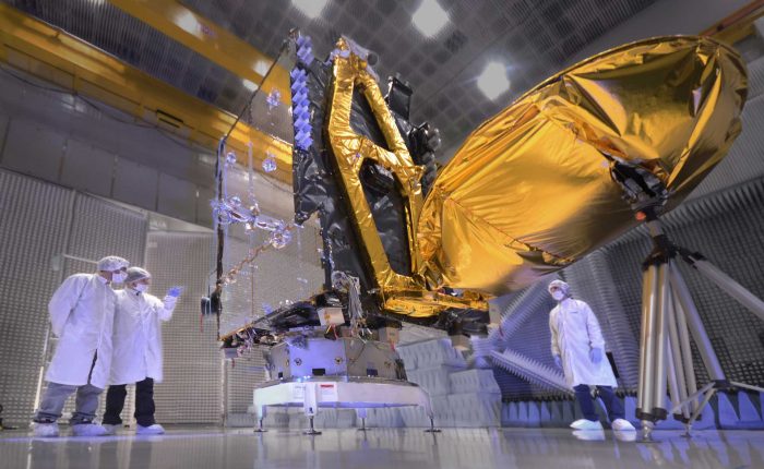 Tres ingenieros observando el cuerpo de un satélite en el Centro de Ensayos de Alta Tecnología Sociedad Anónima CEATSA