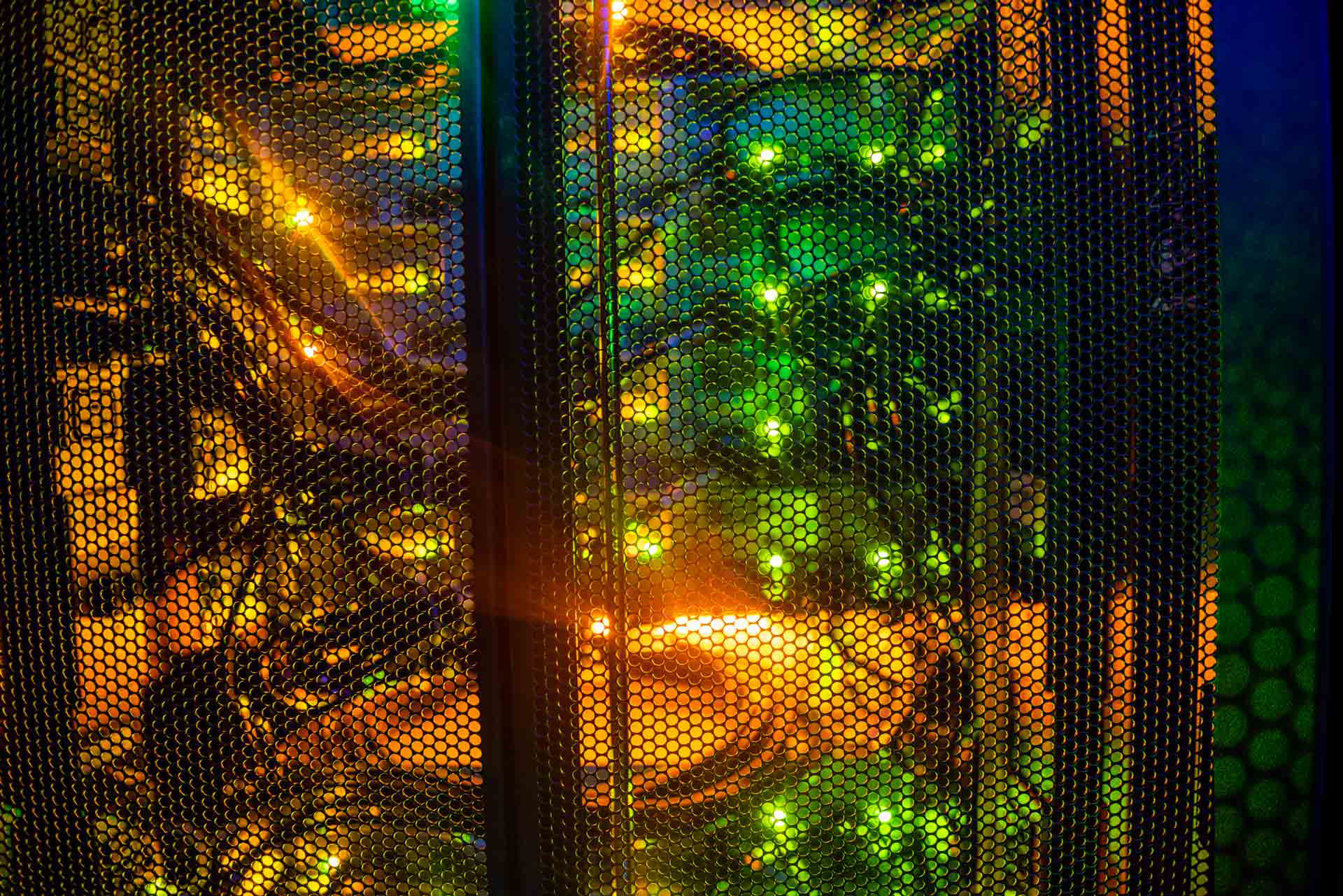 Puerta microperforada de armario rack con cables y luces en una sala del Centro Nacional de Datos.