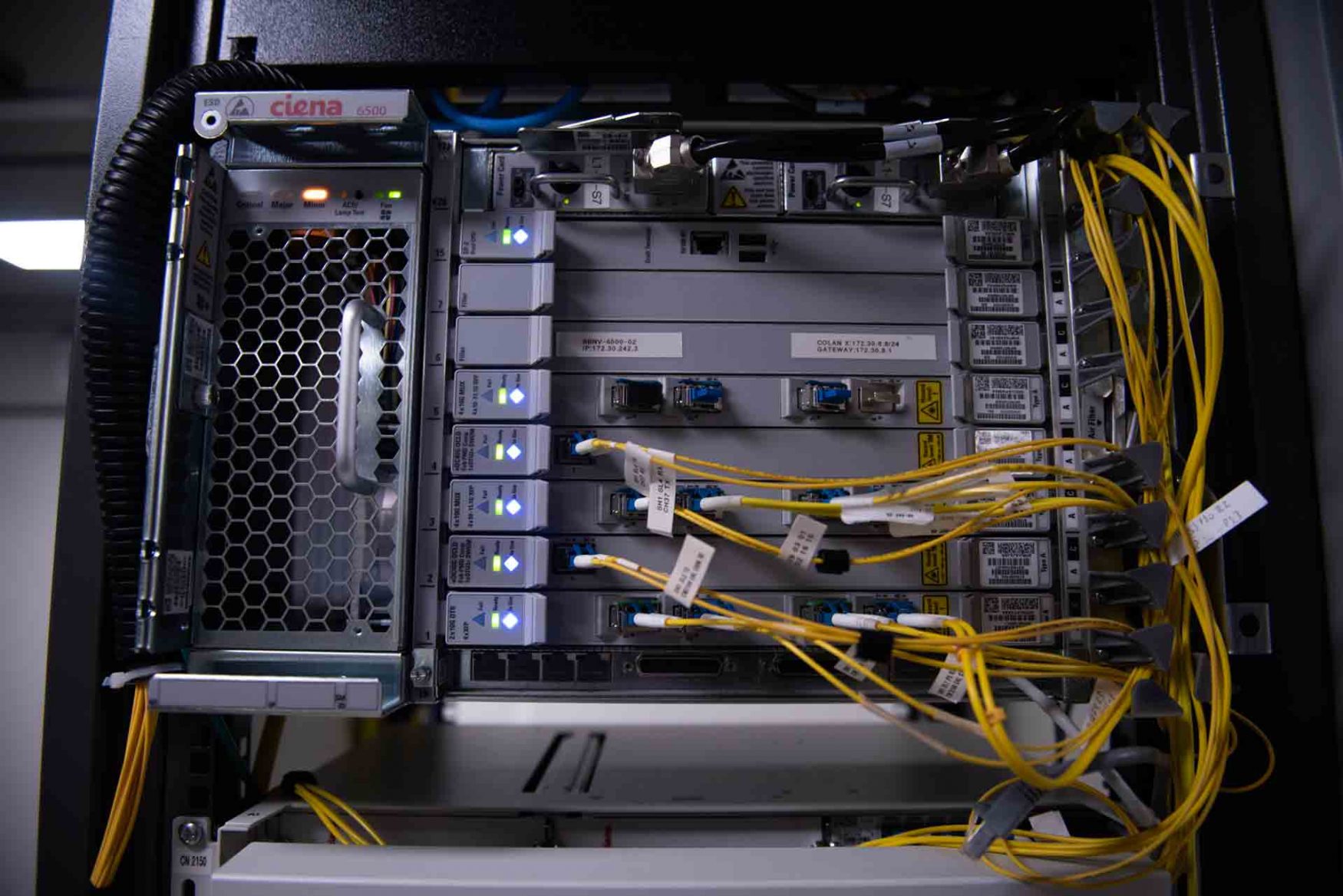 Interior de un rack con luces, entrada de conectores y cables amarillos conectados en una sala del Centro Nacional de Datos.
