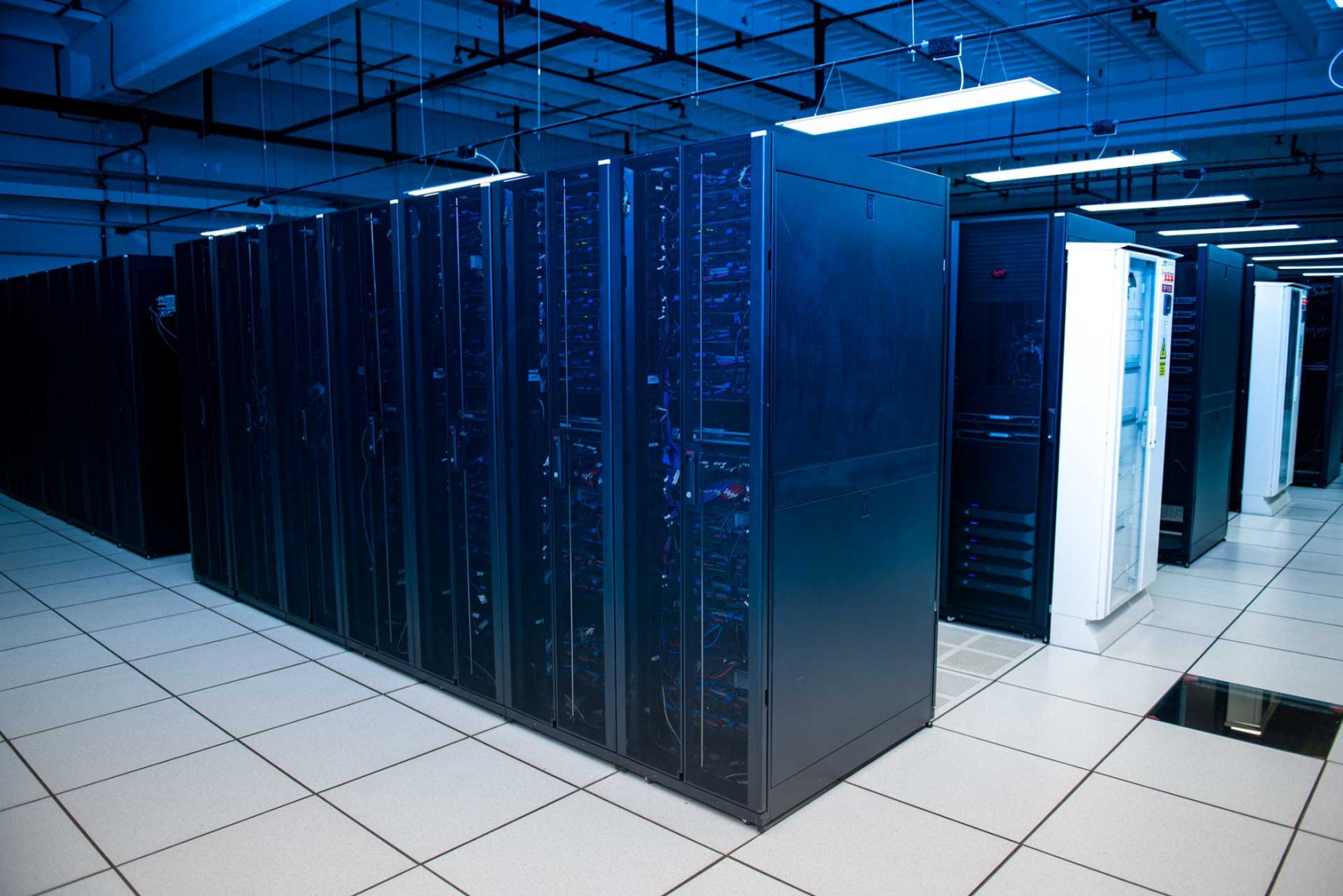 Hilera y filas de racks cerrados e iluminados en una sala del Centro Nacional de Datos.