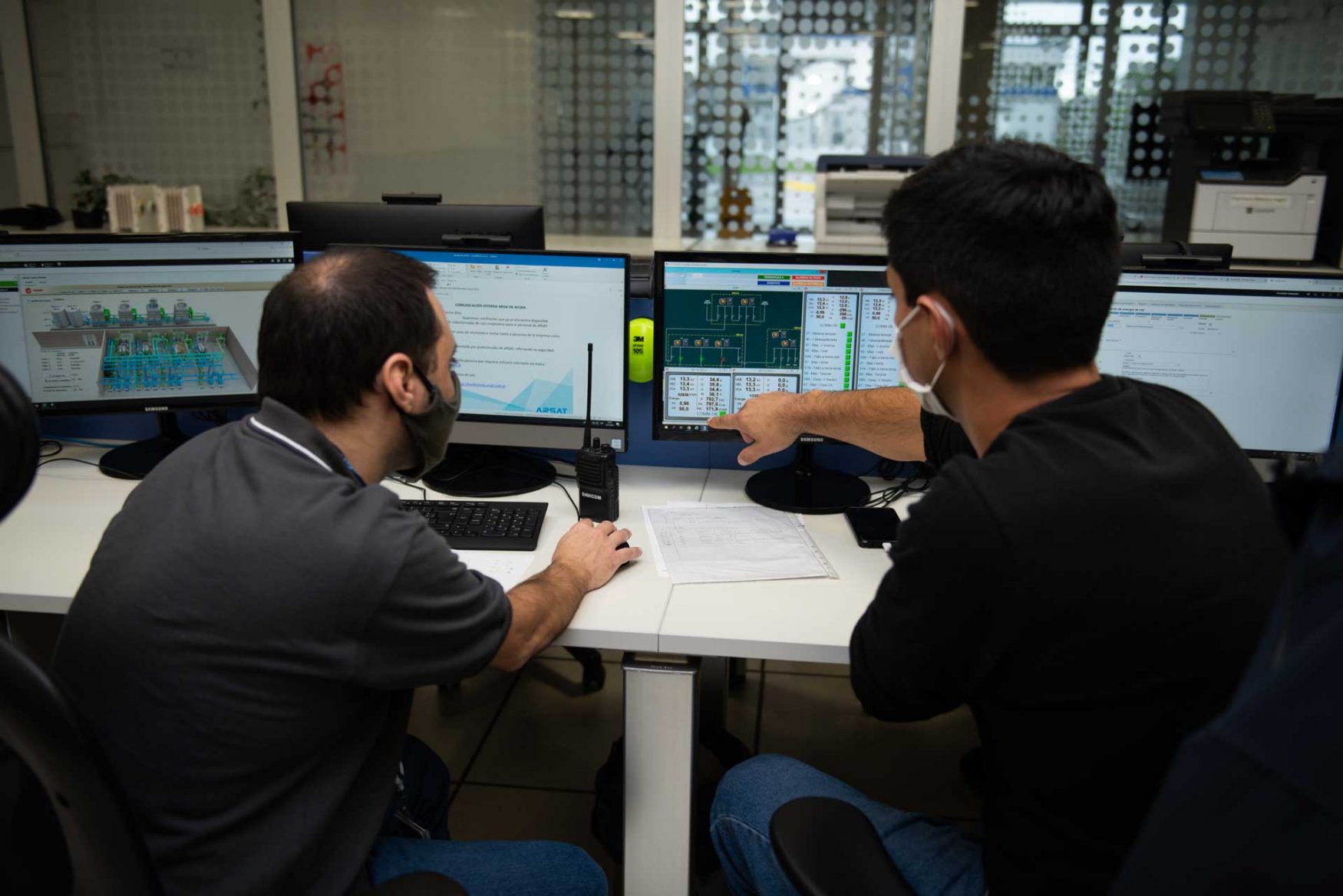 Dos técnicos monitorean las salas desde una computadora y 4 monitores, en el Centro de Operaciones del Centro Nacional de Datos.