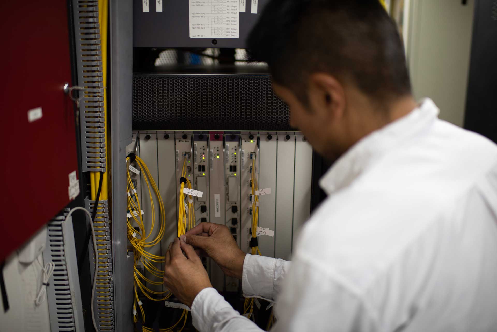 Un técnico de espaldas conecta cables en un equipo de un shelter de la Red Federal de Fibra Óptica.